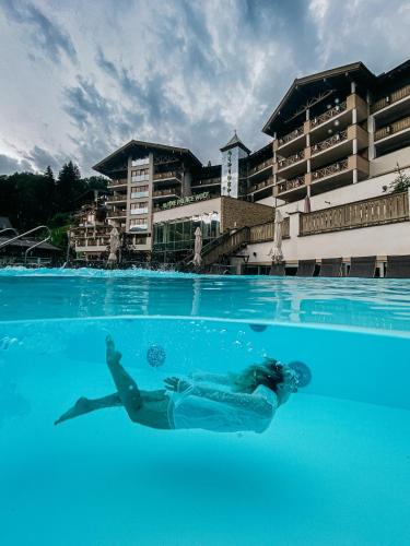 a person swimming in the water in a swimming pool at Stammhaus im Hotel Alpine Palace in Saalbach Hinterglemm