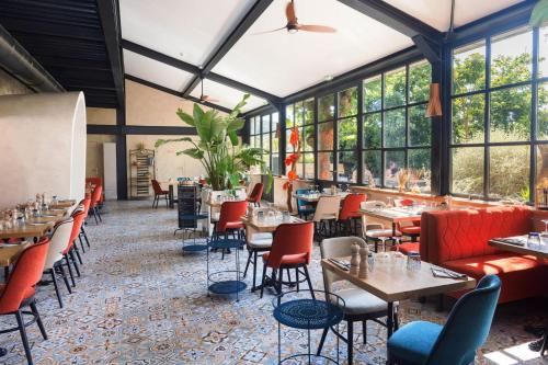 ein Restaurant mit Tischen und Stühlen und Fenstern in der Unterkunft LOU CALEN in Cotignac