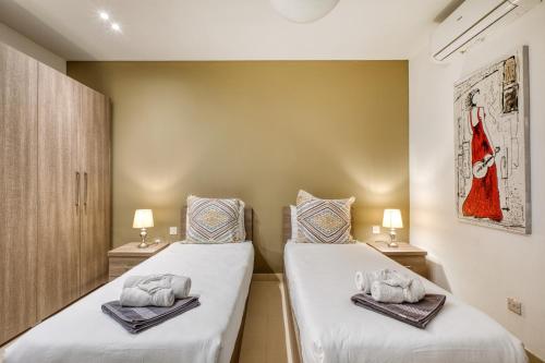 two beds in a room with towels on them at Beautiful Penthouse with pool and terrace in Is-Swieqi