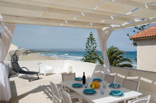 a table and chairs on a patio with a view of the beach at Almaga Apartments - San Lorenzo, Marzamemi in Noto
