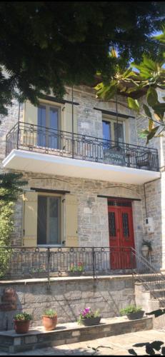 a building with a red door and a balcony at Αρχοντικό Πρεπάλα in Neochori