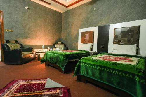 a room with two beds and a living room with a couch at Hotel the Lodges inn in Multan