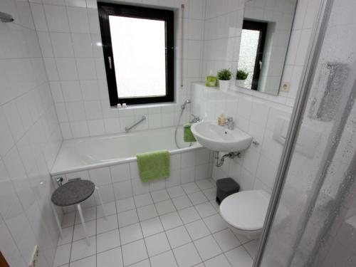 La salle de bains blanche est pourvue d'un lavabo, de toilettes et d'une baignoire. dans l'établissement Seepark Falk Wohnung Nr -2-, à Fribourg-en-Brisgau