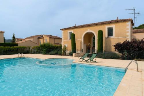 - une piscine avec 2 chaises longues devant une maison dans l'établissement Villa climatisée avec piscine, à Vaison-la-Romaine