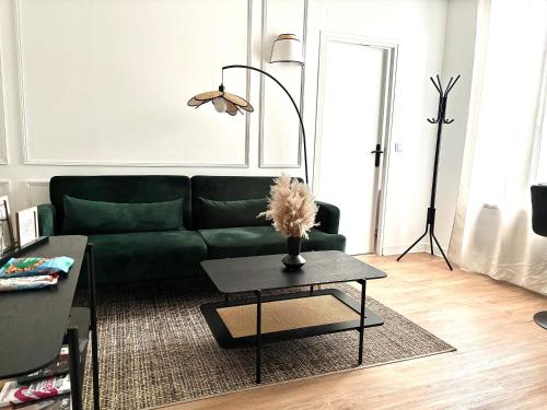 een woonkamer met een groene bank en een tafel bij Eleven Arene BY PRIMO C0NCIERGERIE in Bourges
