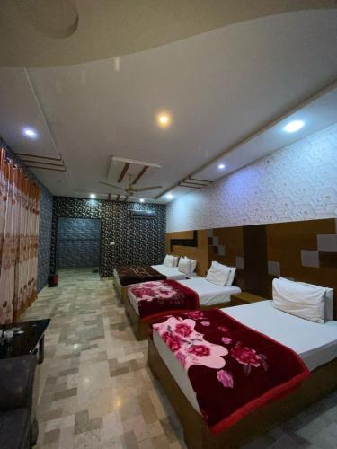 a hotel room with three beds and a couch at Hotel the Lodges inn in Multan