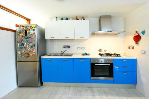 a kitchen with blue cabinets and a refrigerator at Villa con piscina in parco privato in Agnone