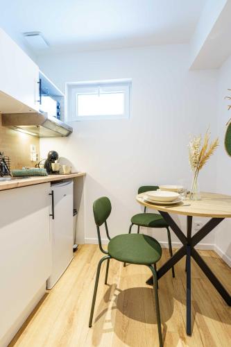 une cuisine avec une table et deux chaises vertes dans l'établissement Studio Détente 2 pers wifi gare, à Saint-Quentin