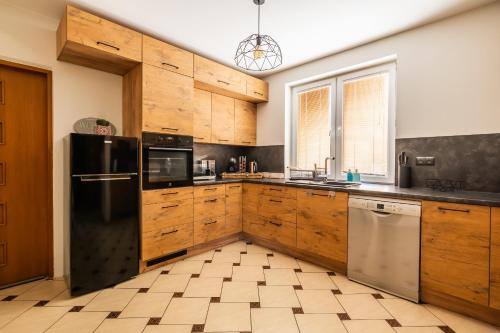 a kitchen with wooden cabinets and a black refrigerator at Willa Garian in Woryty