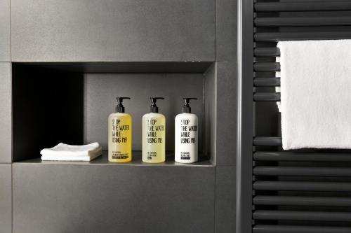 three bottles of soap sitting on a shelf in a bathroom at Stadthotel Brunner in Schladming