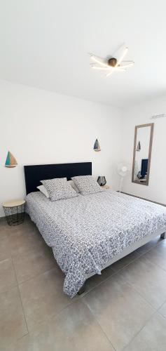 - une chambre blanche avec un grand lit et une tête de lit noire dans l'établissement O'Cap, à Antibes