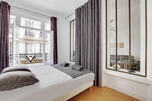 une chambre avec un lit et une grande fenêtre dans l'établissement Moderne 3 pièces au coeur des Champs-Elysées, à Paris