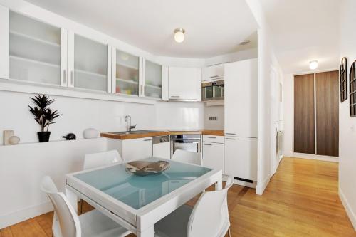 une cuisine avec des armoires blanches et une table et des chaises dans l'établissement Moderne 3 pièces au coeur des Champs-Elysées, à Paris