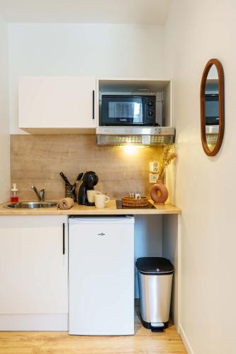 une petite cuisine avec un four micro-ondes au-dessus d'un comptoir dans l'établissement Studio Relax 2pers wifi, à Saint-Quentin