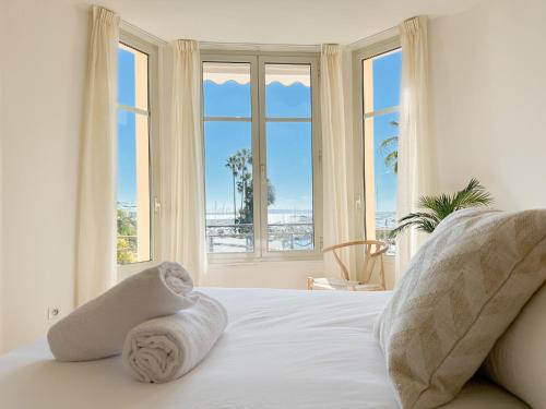 - une chambre avec un lit doté de draps blancs et de fenêtres dans l'établissement Cornut 4A, à Cannes