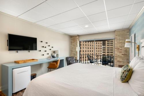 a bedroom with a bed and a desk with a tv at Riverwalk Plaza Hotel in San Antonio