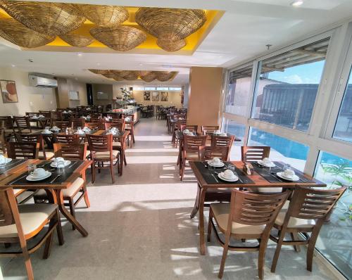 a restaurant with wooden tables and chairs and windows at Bali Mar Hotel in Natal
