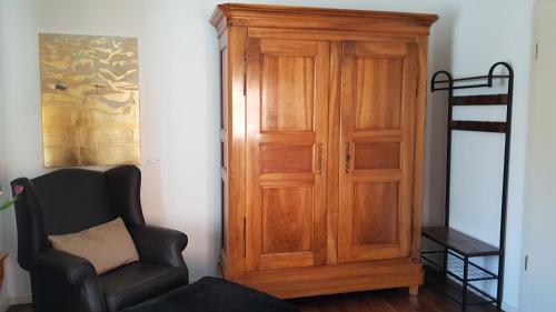 a room with a wooden cabinet and a chair at Remise Heiliger See in Potsdam