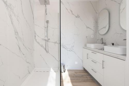 La salle de bains blanche est pourvue de murs en marbre et d'une douche. dans l'établissement Maison paisible au pied de la Sainte Victoire Idéale pour un séjour en famille ou entre amis, à Beaurecueil