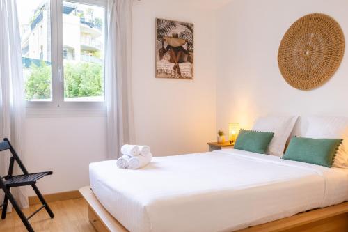 un lit blanc dans une chambre avec une fenêtre dans l'établissement Les Glycines, à Menton