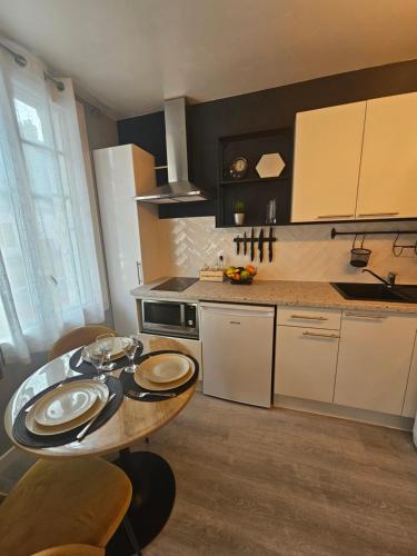 une cuisine avec une table avec des assiettes dessus dans l'établissement Le Deauvillais Studio en plein cœur de Deauville, à Deauville