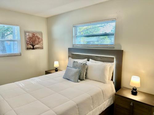 a bedroom with a large white bed with two windows at Orlando Luxe Retreat with Private Pool in Orlando
