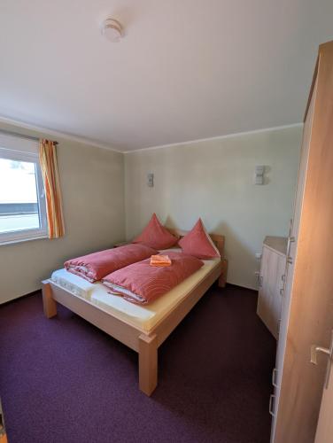 a bedroom with a bed with red pillows on it at Ferienwohnung Koserow in Koserow