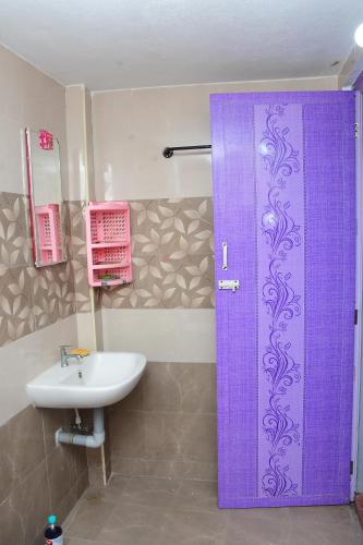 a bathroom with a purple door and a sink at Greenfields Pondicherry- An Eco-friendly farm stay in Villianur