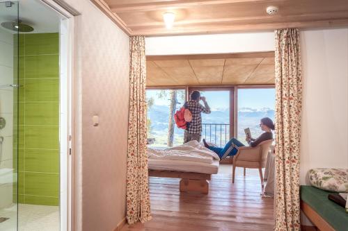 a couple standing in a room with a bed and a window at Biohotel Grafenast in Pill