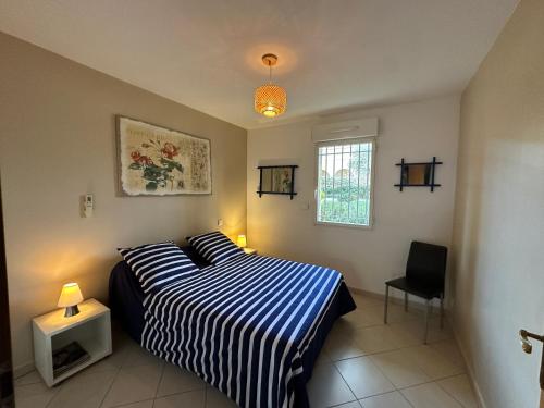 une chambre avec un lit avec une couverture rayée bleue et blanche dans l'établissement Appartement 2 pièces, 4 couchages L'Ile-Rousse, à LʼÎle-Rousse