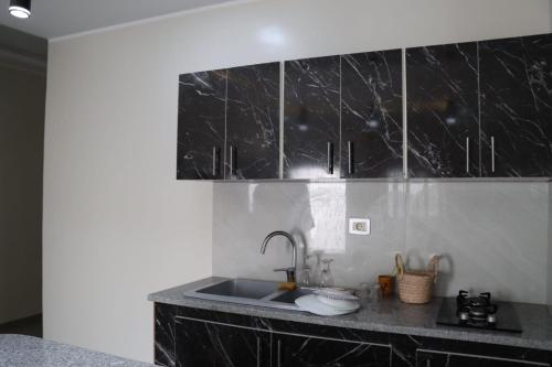 a kitchen with a sink and black counter top at Al Yasmine residence in Douz