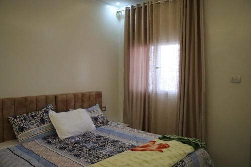 a bedroom with a bed and a window with curtains at Al Yasmine residence in Douz