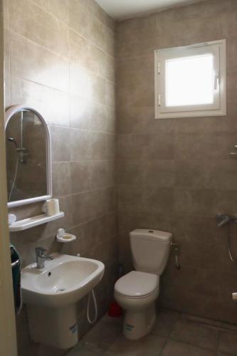 a bathroom with a toilet and a sink and a window at Al Yasmine residence in Douz