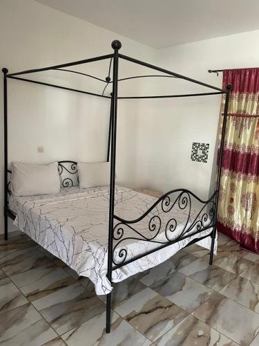 Cama con dosel de metal negro en una habitación en Villa Lydia Saly, en Saly Portudal