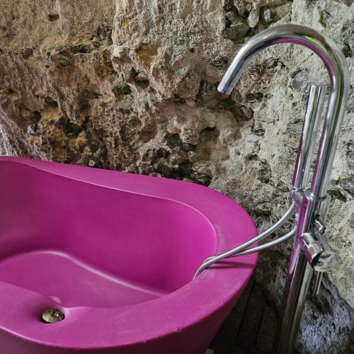 une baignoire rose contre un mur en pierre dans l'établissement La suite des fouleries, à Châteaudun