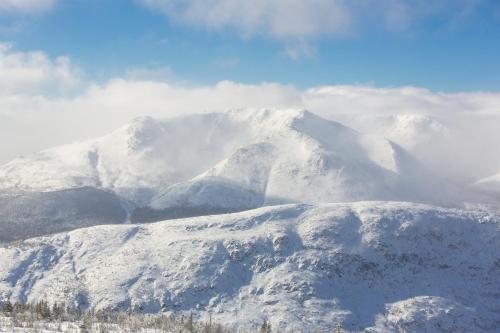 a mountain covered in snow with clouds in the background at Gîte du Mont-Albert - Sepaq in Sainte-Anne-des-Monts