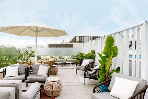 an outdoor patio with chairs and tables and an umbrella at Radisson Collection Hotel, Magdalena Plaza Sevilla in Seville