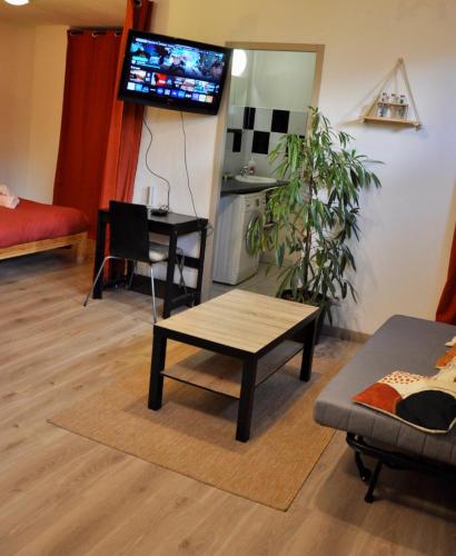 un salon avec une table et une télévision au mur dans l'établissement Le Spot de Bayard - Hypercentre Toulouse, Gare Matabiau, Accueil h24, Wi-Fi, à Toulouse