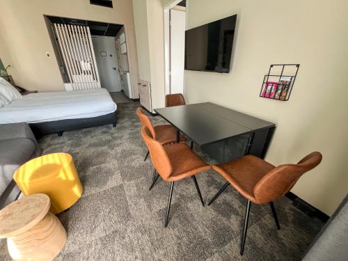 a room with a table and chairs and a bed at Otium Hotel Roosendaal in Roosendaal
