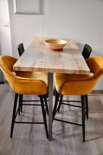 - une table en bois avec des chaises orange et un bol sur le dessus dans l'établissement Le Spot de Bayard - Hypercentre Toulouse, Gare Matabiau, Accueil h24, Wi-Fi, à Toulouse
