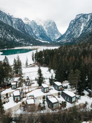 a group of houses in the snow next to a lake at Skyview Chalets am Camping Toblacher See in Dobbiaco