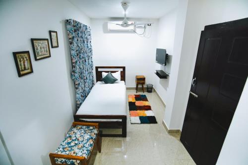 a room with a bed and a bench and a door at Nivasa Homestay - Khanapara Guwahati in Guwahati