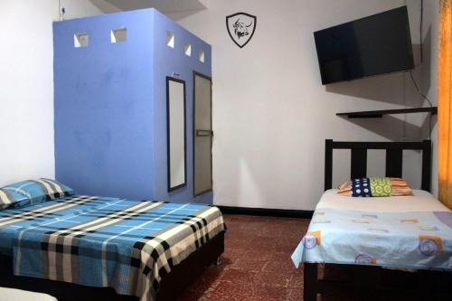 a room with two beds and a flat screen tv at Hotel El Barcino in Neiva