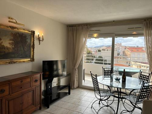 un salon avec une table avec des chaises et une télévision dans l'établissement La Croisette I T2, à Cannes