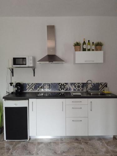 a kitchen with white cabinets and a stove top oven at Finca el Gaudi, casita Catharina in L'Ampolla