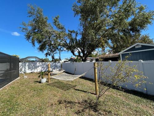 a fence with a tree and a hammock in a yard at Coastal Oasis 64th in Bradenton