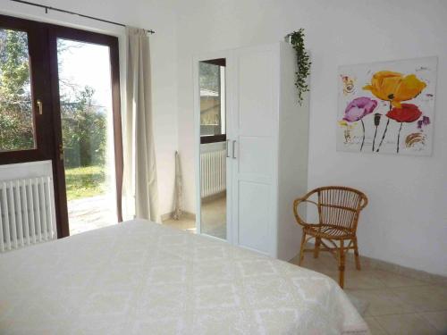 a bedroom with a bed and a chair and a window at Casa Paradiso in Porto Valtravaglia