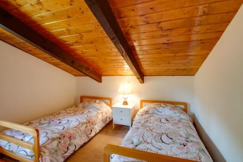 two beds in a bedroom with a wooden ceiling at Mountaintop Condo with Great Mt Washington View in Glen