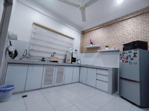 a kitchen with a refrigerator and a sink in it at Amna Homestay Sandakan in Sandakan