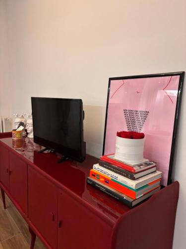a red dresser with a television and a stack of books at Gemmas home in Uboldo
